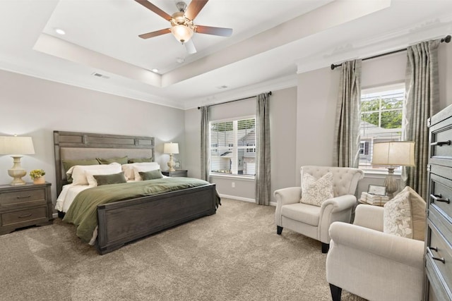 bedroom with light carpet, visible vents, multiple windows, and a tray ceiling