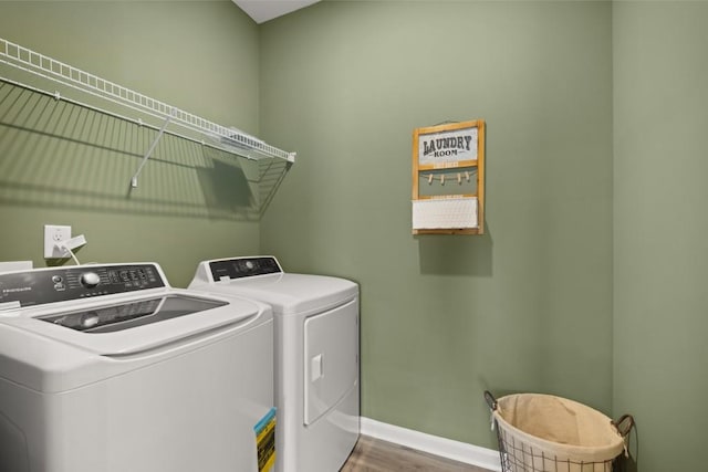 washroom with laundry area, washing machine and dryer, baseboards, and wood finished floors