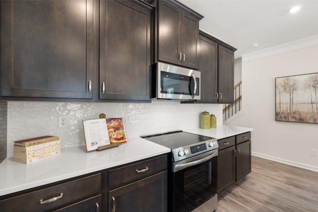 kitchen featuring dark brown cabinetry, decorative backsplash, appliances with stainless steel finishes, light countertops, and light wood-style floors