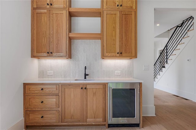 bar area featuring a sink, beverage cooler, backsplash, and stairs