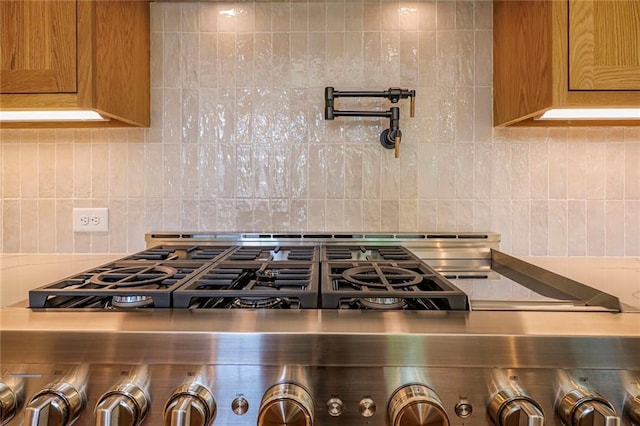 kitchen view of pot filler, tasteful backsplash, and brown cabinetry