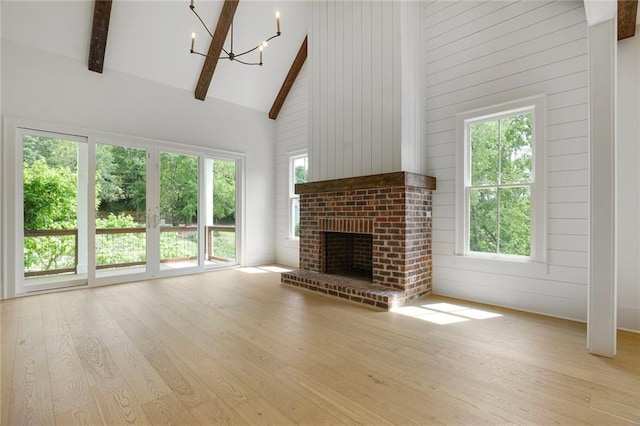 unfurnished living room with high vaulted ceiling, wood finished floors, a chandelier, beam ceiling, and a fireplace