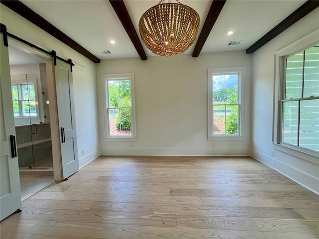 empty room featuring beamed ceiling, baseboards, light wood-style flooring, a barn door, and plenty of natural light