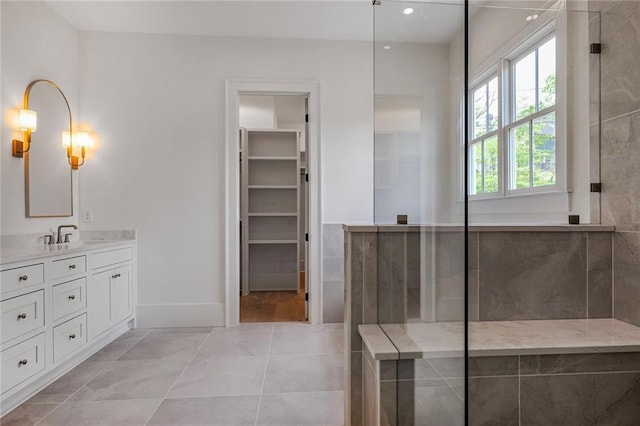 bathroom with vanity, a walk in closet, baseboards, and recessed lighting