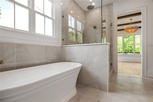 full bath featuring plenty of natural light, a shower stall, a soaking tub, and tile walls