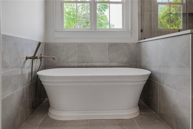 bathroom featuring tile walls, a freestanding bath, and tile patterned floors