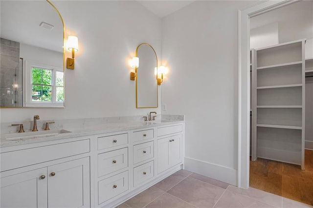 bathroom with double vanity, a tile shower, baseboards, and tile patterned flooring