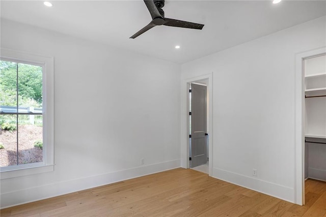 unfurnished bedroom featuring a spacious closet, light wood finished floors, recessed lighting, a closet, and baseboards