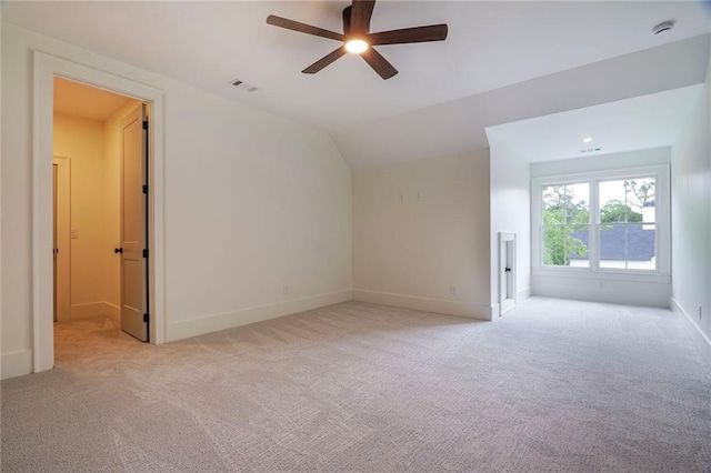 empty room featuring ceiling fan, light colored carpet, a smoke detector, lofted ceiling, and baseboards