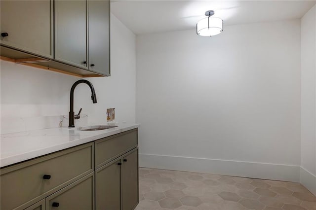 bar area featuring a sink, baseboards, and light flooring