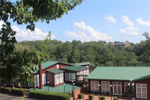 view of property with uncovered parking and a wooded view