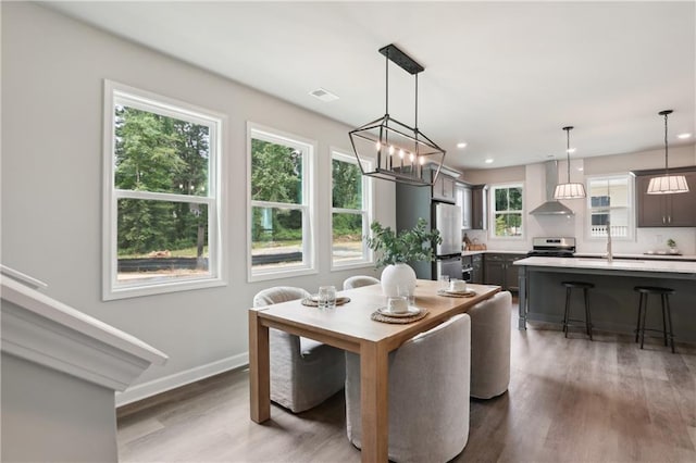 dining room featuring baseboards, visible vents, wood finished floors, and recessed lighting