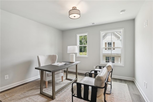 office space featuring wood finished floors, visible vents, and baseboards