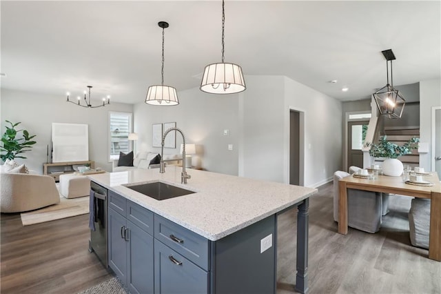 kitchen with dishwashing machine, light stone counters, open floor plan, wood finished floors, and a sink