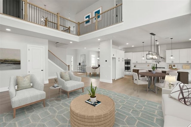 living room featuring an inviting chandelier, light hardwood / wood-style flooring, and a high ceiling