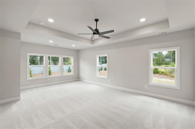 carpeted spare room featuring ceiling fan and a tray ceiling