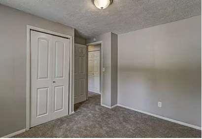 unfurnished bedroom with dark carpet and a closet