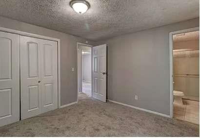 unfurnished bedroom featuring ensuite bathroom, light carpet, and a closet