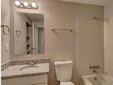 full bathroom with tiled shower / bath, vanity, and toilet