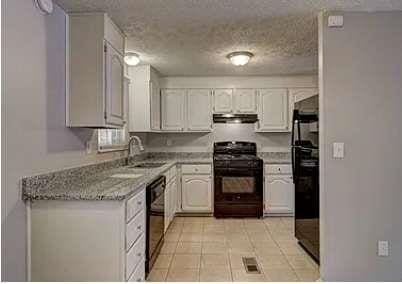 kitchen with white cabinetry, sink, black appliances, light stone countertops, and a textured ceiling