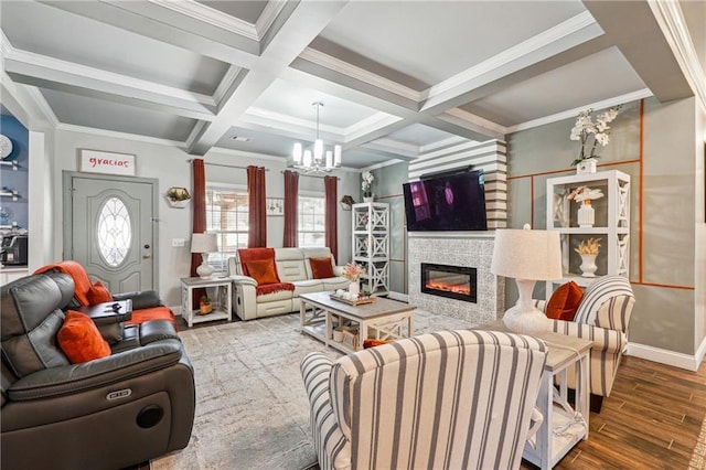 living room with wood finished floors, coffered ceiling, ornamental molding, a glass covered fireplace, and a chandelier