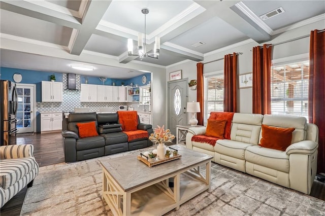 living area featuring wood finished floors, visible vents, coffered ceiling, an inviting chandelier, and beamed ceiling