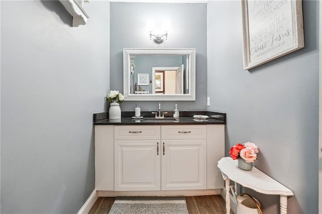 bathroom with baseboards, wood finished floors, and vanity