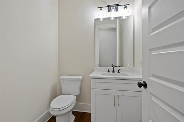 bathroom featuring vanity, toilet, wood finished floors, and baseboards