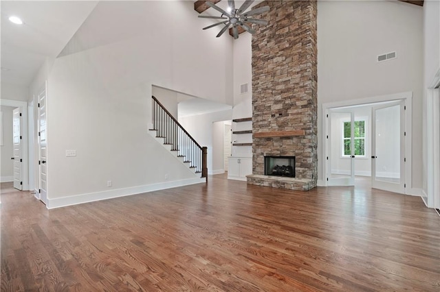 unfurnished living room with visible vents, baseboards, stairway, a fireplace, and wood finished floors