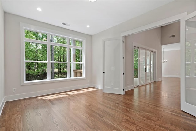 spare room with visible vents, baseboards, an inviting chandelier, and wood finished floors