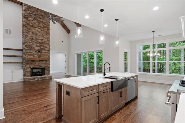 kitchen featuring visible vents, a sink, plenty of natural light, a stone fireplace, and dishwasher