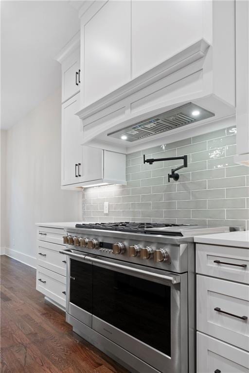 kitchen with high end stove, custom range hood, light countertops, decorative backsplash, and dark wood-style flooring