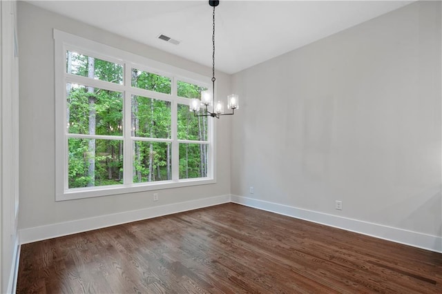 spare room with visible vents, baseboards, dark wood-style floors, and a chandelier