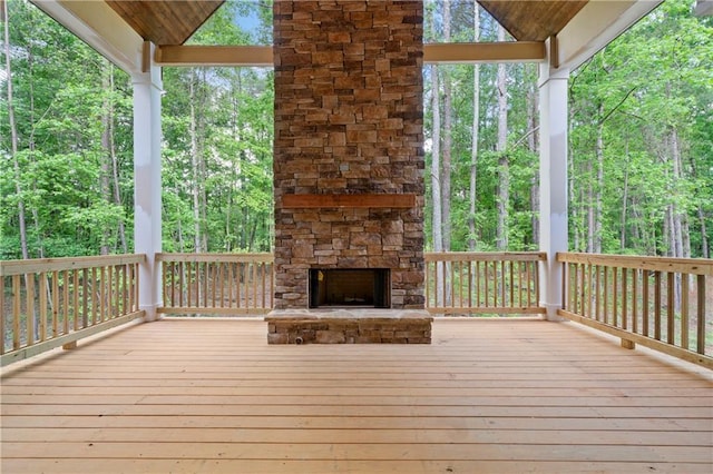 wooden deck with a forest view and an outdoor stone fireplace