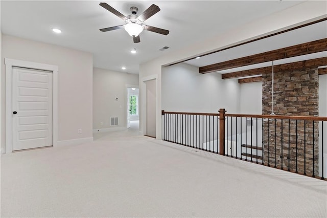 spare room with beamed ceiling, carpet, and visible vents