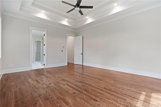 unfurnished bedroom featuring baseboards, a tray ceiling, recessed lighting, ensuite bathroom, and wood finished floors