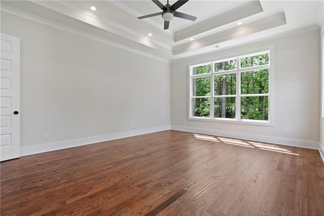 unfurnished room featuring a ceiling fan, baseboards, a tray ceiling, dark wood-style flooring, and ornamental molding