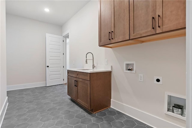 washroom featuring a sink, cabinet space, baseboards, hookup for an electric dryer, and hookup for a washing machine