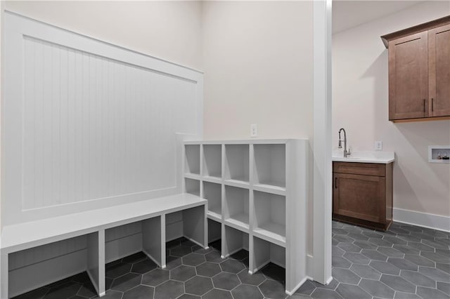 mudroom featuring dark tile patterned floors, baseboards, and a sink