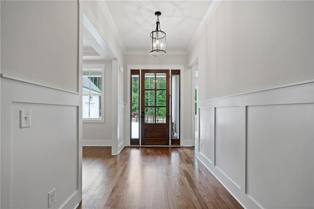 foyer featuring a decorative wall, wood finished floors, a chandelier, and ornamental molding