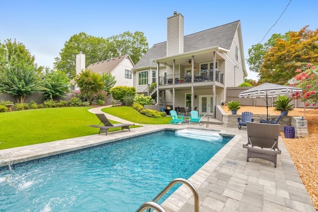 rear view of property featuring a yard, a patio area, a balcony, and ceiling fan