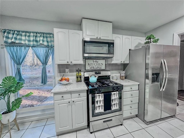 kitchen featuring decorative backsplash, light tile patterned floors, white cabinetry, and appliances with stainless steel finishes