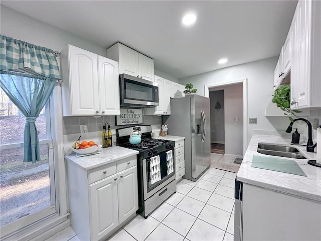 kitchen featuring decorative backsplash, sink, white cabinetry, and appliances with stainless steel finishes