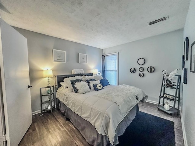 bedroom with a textured ceiling and dark hardwood / wood-style floors