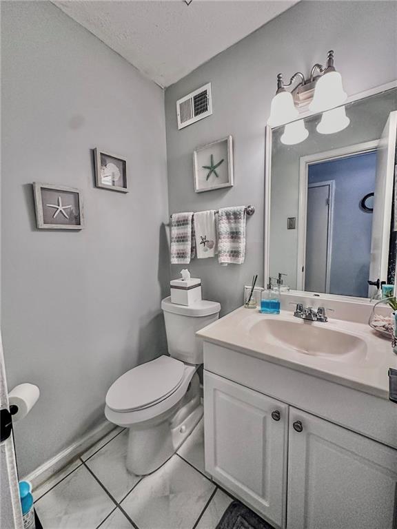 bathroom with vanity, toilet, a textured ceiling, and tile patterned flooring