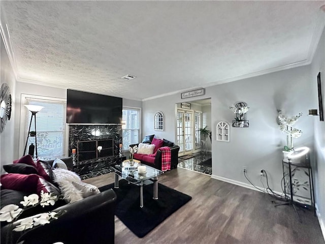 living room featuring a fireplace, hardwood / wood-style floors, a textured ceiling, and ornamental molding