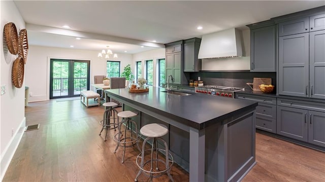 kitchen featuring light wood-type flooring, a breakfast bar area, an island with sink, and sink