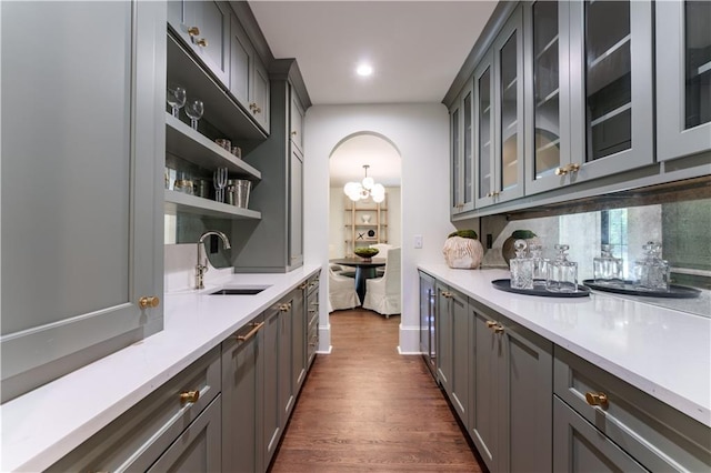 bar with gray cabinets, tasteful backsplash, sink, and dark hardwood / wood-style floors