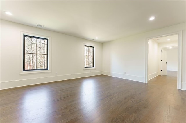 spare room with a wealth of natural light and dark hardwood / wood-style floors