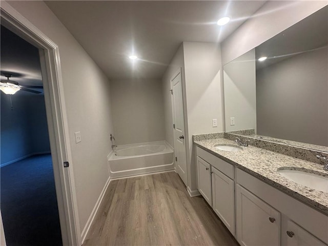 11045 Shadow Creek Ter, Hampton, GA 30228 - bathroom with wood finished floors, double vanity, a garden tub, baseboards, and ceiling fan